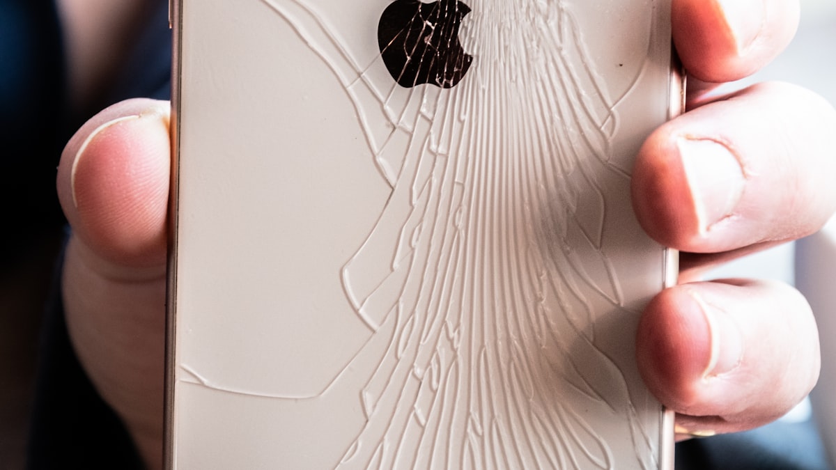 Persoana tinand un iPhone cu ecran spart